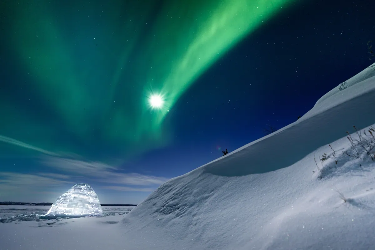 Large glowing igloo illuminated from within under vivid aurora